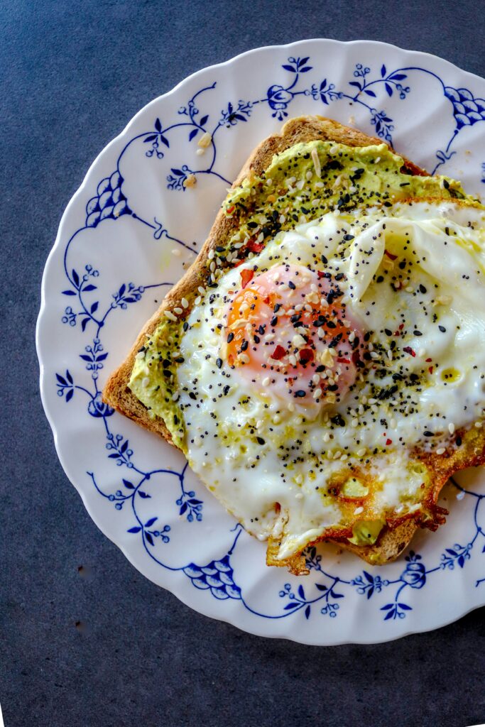 delicious avocado toast with and egg on top and seasoning placed on a pretty plate for homeschool mama