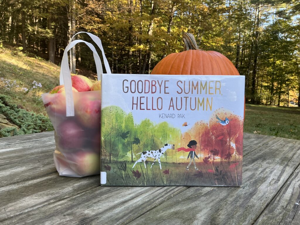 Goodbye Summer, Hello Fall book on a picnic table with a pumpkin