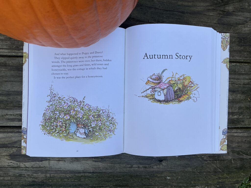 Book opened to the title page of Autumn Story, on a table with a pumpkin