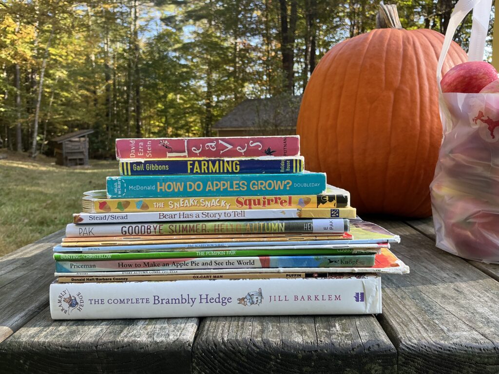 Stack of books on a picnic table with a pumpkin