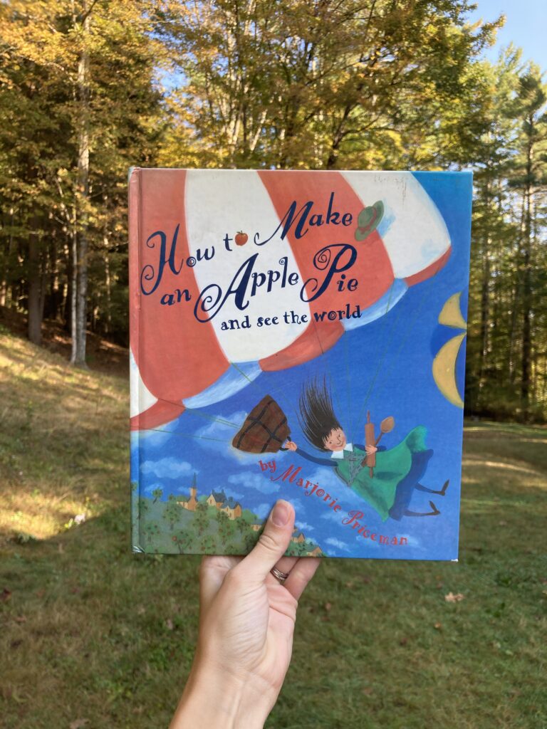 Person holding up a book about baking apple pie with trees in the background