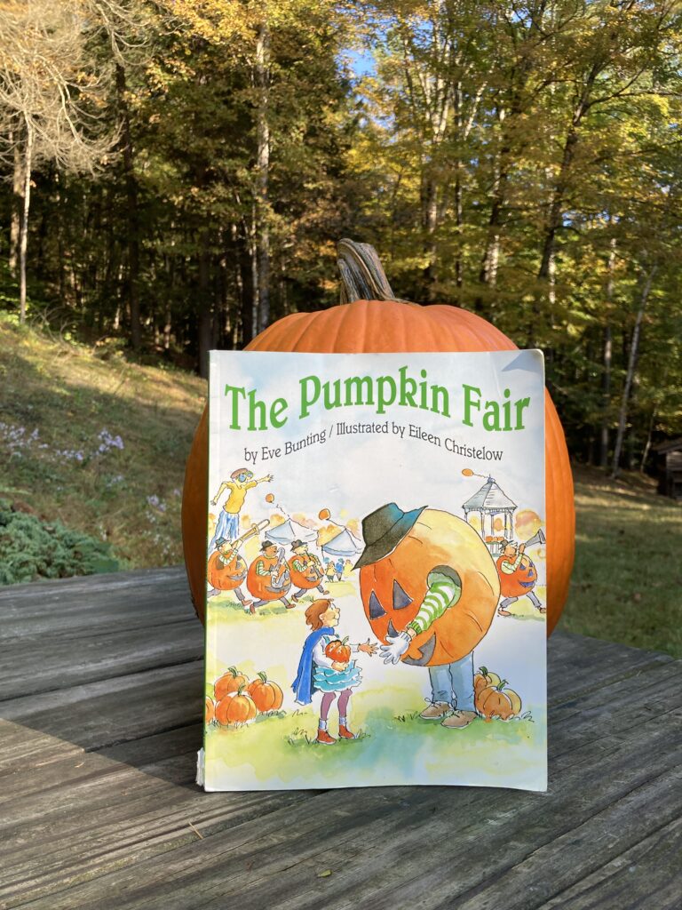 The pumpkin fair book propped against a pumpkin on a picnic table