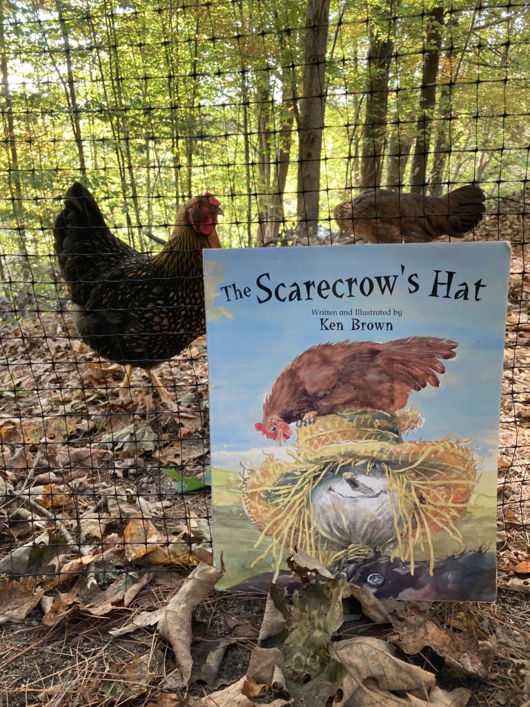 Book leaning up against a fence with chickens behind it in the autumn season