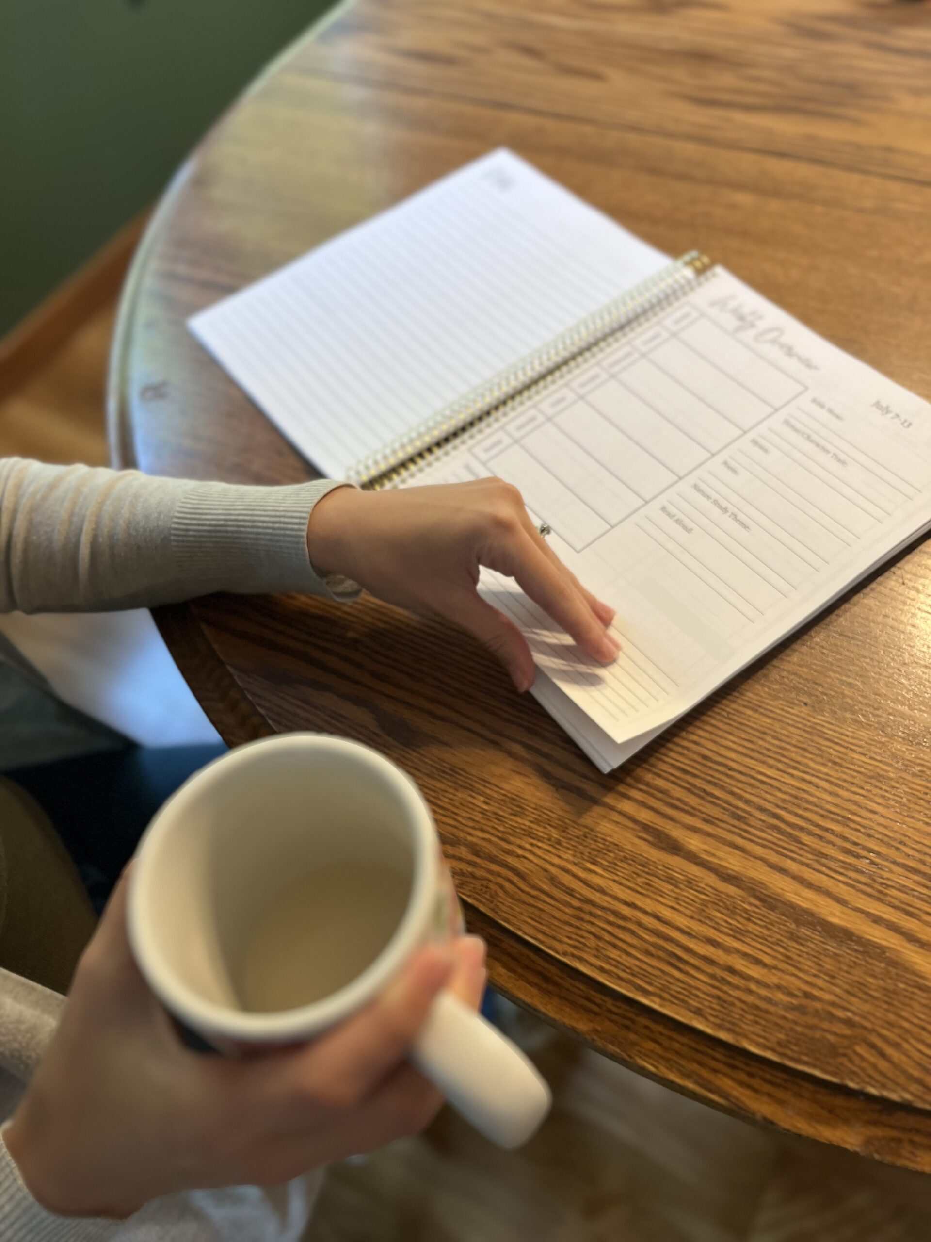 Woman flipping through a planner while she sips her morning coffee
