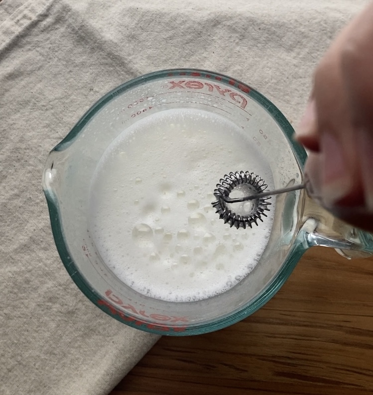 milk frother blending milk in a measuring glass